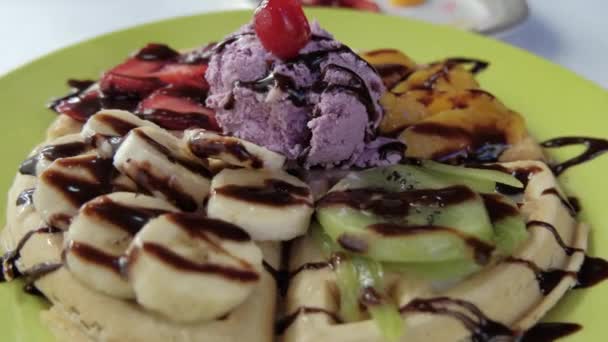 Παγωτό, φρούτα και σιρόπι σοκολάτας πάνω από μια βάφλα - Πλάνα, βίντεο