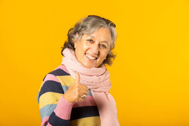 Femme âgée en vêtements décontractés montre ok signe sur un fond jaune - Photo, image