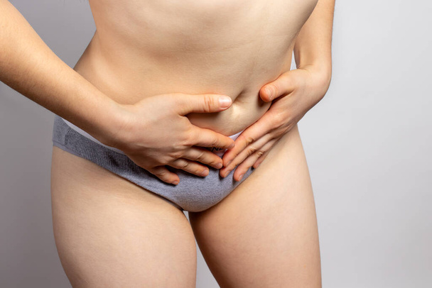La mujer tiene un dolor de estómago durante la menstruación o dolores de tracción en la parte inferior del abdomen en los ovarios durante el embarazo. Síndrome premenstrual, ovario poliquístico, endometriosis - enfermedades ginecológicas. - Foto, imagen