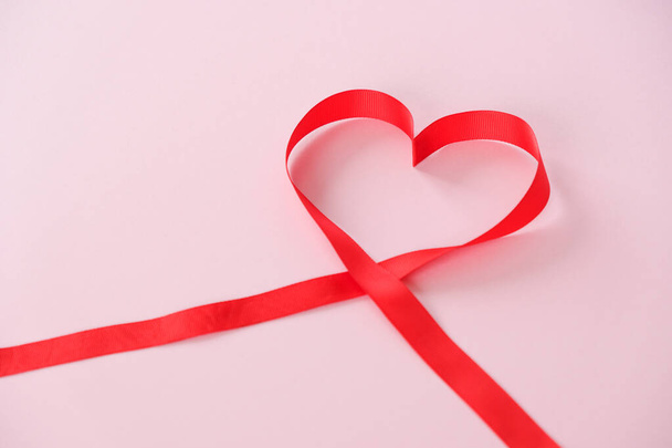 red ribbon in the shape of a heart on a pink background - Zdjęcie, obraz