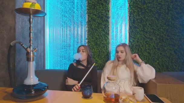 Zwei Freundinnen sitzen in Shisha-Bar, rauchen und reden - Filmmaterial, Video