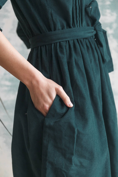 beautiful green corduroy dress on a girl close-up. Hand on the belt - Foto, imagen