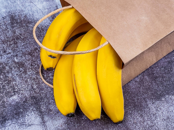 Bunch of bananas in a paper bag on the table - Photo, image