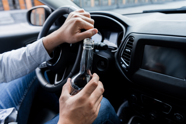 partial view of man holding bottle of whiskey while driving car - Foto, Imagem