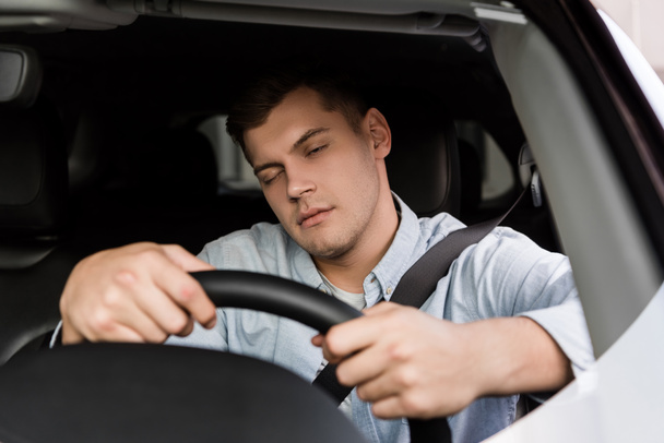 Μεθυσμένος που αποκοιμιέται ενώ οδηγεί αυτοκίνητο, θολή πρόσοψη - Φωτογραφία, εικόνα