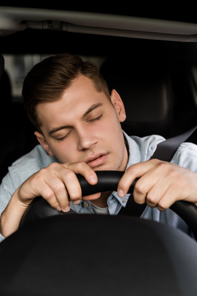 Betrunkener schläft am Steuer in Auto auf verschwommenem Untergrund - Foto, Bild