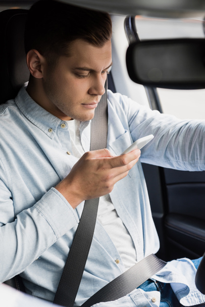 young man messaging on mobile phone while driving car - Photo, Image