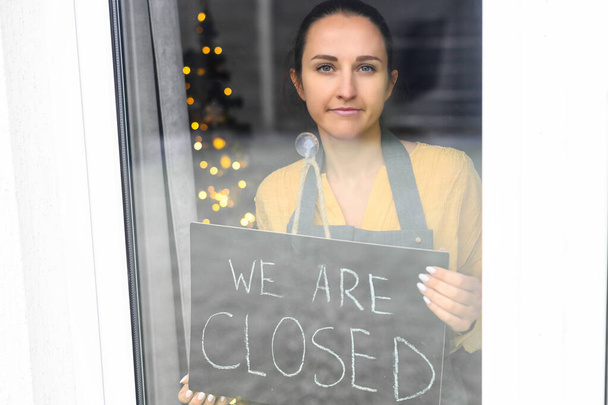 A young woman is holding closed sign - Photo, Image