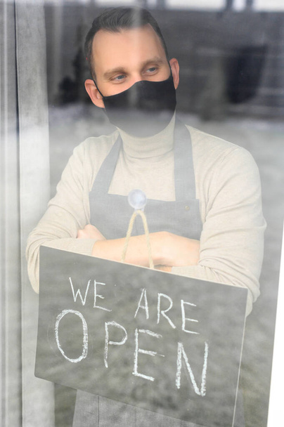 Young man holding open sign in cafe - Foto, Imagen