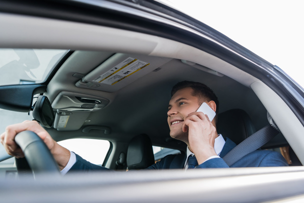 Allegro uomo d'affari che parla sullo smartphone mentre guida auto in primo piano sfocato - Foto, immagini