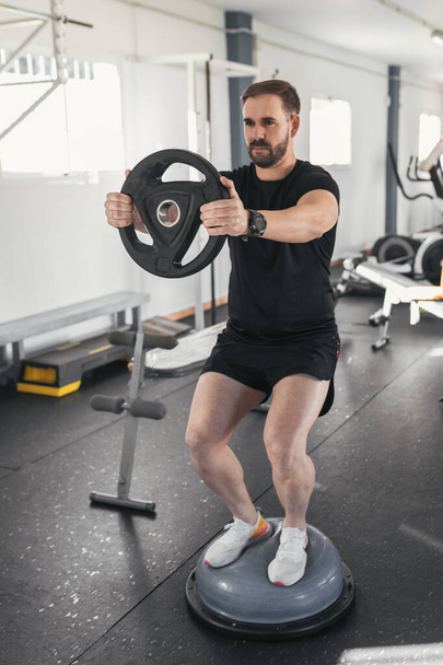 man caucasian handsome and big muscle in sportswear. Young man holding weights during an exercise class in a gym. Healthy sports lifestyle, Fitness concept.Vertical. - Foto, Imagen