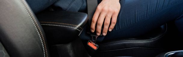 Cropped view of man locking seatbelt in car, banner - 写真・画像