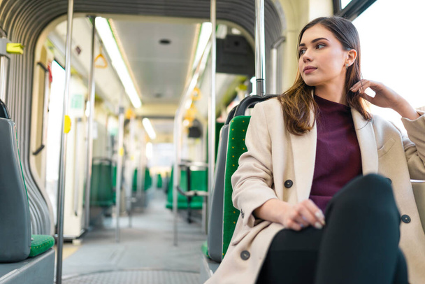 若い女の子は近代的な都市トラムに乗っています。公共交通機関に座っている女性旅客 - 写真・画像