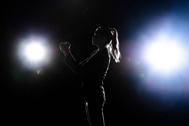 Silhouet van vrouw poseren geïsoleerd op donkere achtergrond in lantaarns licht - Foto, afbeelding