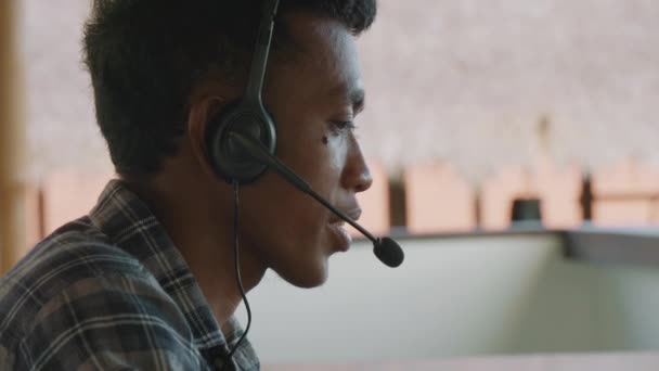 zbliżenie w górę w młody Azjata człowiek w kratkę koszula i słuchawki konsultant klient przez telefon - Materiał filmowy, wideo
