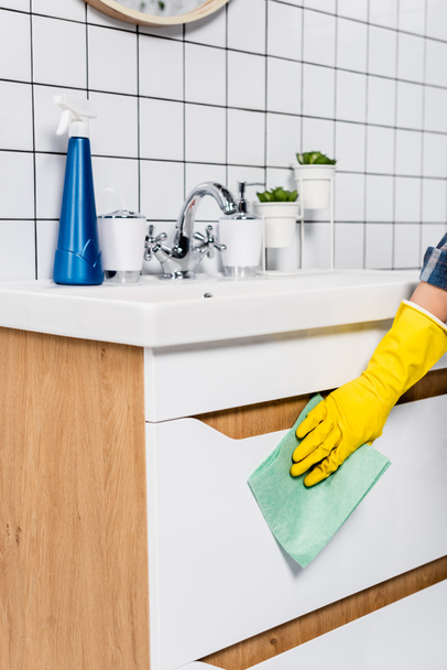Vista recortada del lado de limpieza de la mujer del fregadero con trapo cerca del detergente en el baño  - Foto, Imagen