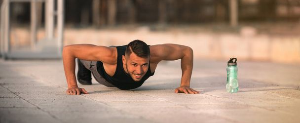 Sportlicher Mann macht Liegestütze. Workout-Übung. Training im Freien. Sport- und Fitnesskonzept - Foto, Bild