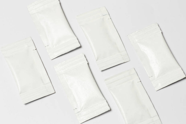 Close-up composition of white sachets on a white background. - Фото, изображение