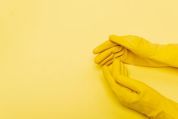 Верхний вид рук в резиновых перчатках на желтом фоне - Фото, изображение