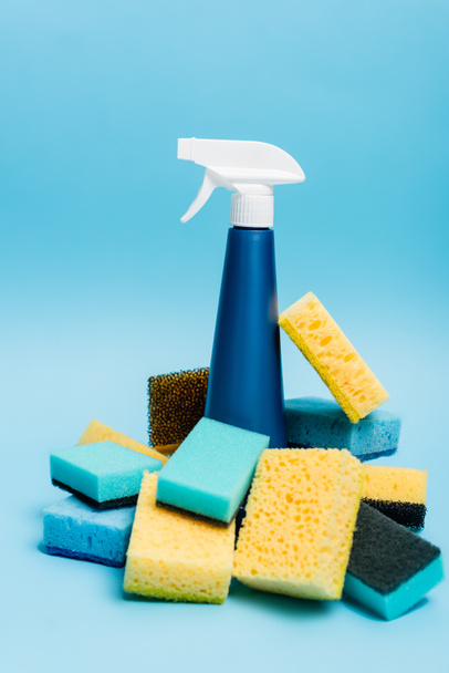 Bottle of detergent and sponges on blurred foreground on blue background - Fotoğraf, Görsel