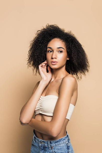 curly young african american woman with bare shoulders looking away on beige  - Photo, Image