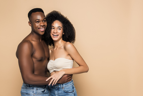 happy african american woman laughing and hugging with cheerful boyfriend isolated on beige - Фото, зображення