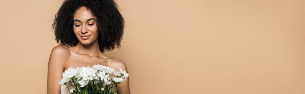 happy african american woman holding flowers isolated on beige, banner - Photo, Image