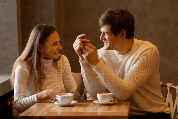 Young couple sitting and talking in caffe with coffee. Valentine day. - Photo, Image