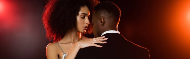 élégante femme afro-américaine embrassant l'homme en tenue formelle sur noir, bannière - Photo, image