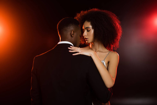 elegant african american woman embracing man in formal wear on black - Foto, imagen