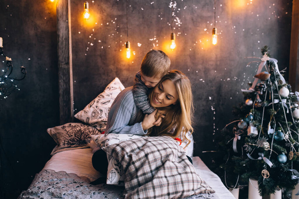 chlapec objímající svou matku na posteli v ložnici - Fotografie, Obrázek