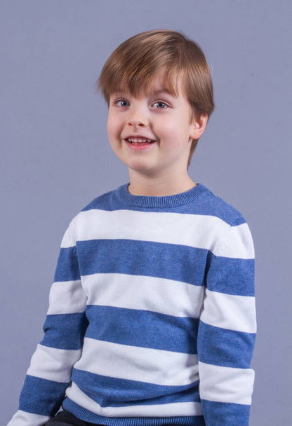 Portret van een schattig jongetje met blond haar, een lachend kind, gelukkige kindertijd, modeluiterlijk. - Foto, afbeelding