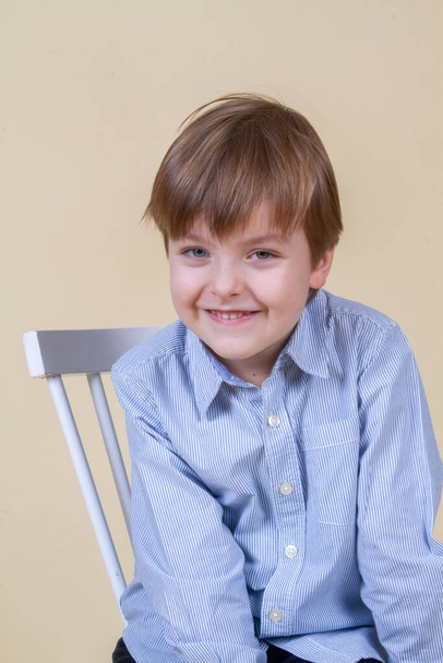 Portrait of a cute little boy with blond hair, a child smiling, happy childhood, model appearance. - Фото, изображение