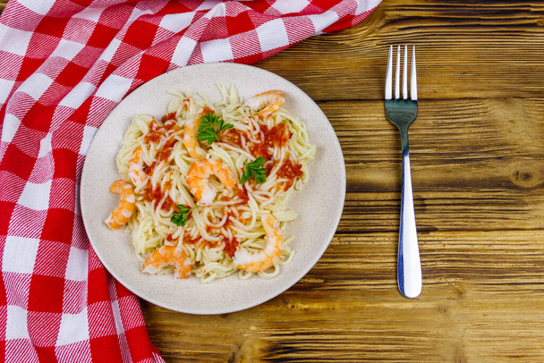 Spagetti tészta garnélával, paradicsomszósszal és petrezselyemmel az asztalon. Felülnézet - Fotó, kép