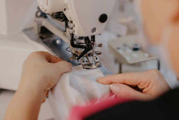 A selective focus shot of seamstress hands working on sewing machine - Фото, зображення