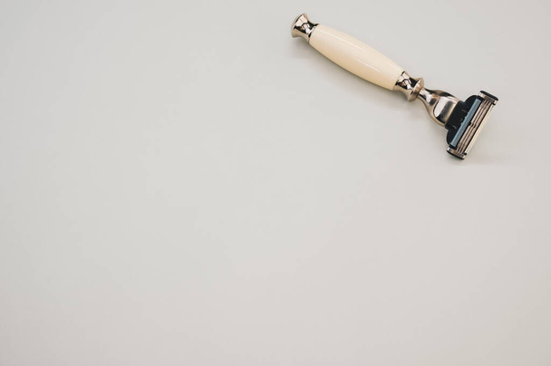 Um tiro de close-up de uma navalha bege e preta isolada em um fundo bronzeado mais suave - Foto, Imagem