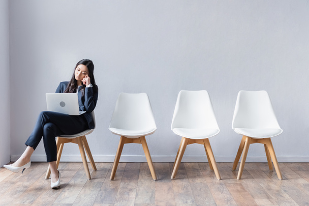 Asiática mujer de negocios utilizando portátil en sala mientras espera entrevista de trabajo  - Foto, Imagen