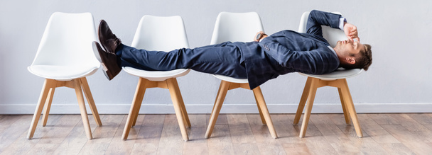 Businessman in formal wear lying on chairs in hall, banner  - Foto, Imagen