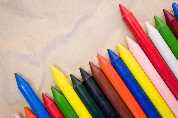 A set of lined up colored wax crayons on recycled paper background - Fotografie, Obrázek