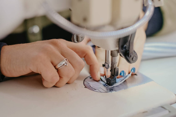 A selective focus shot of seamstress hands working on sewing machine - 写真・画像