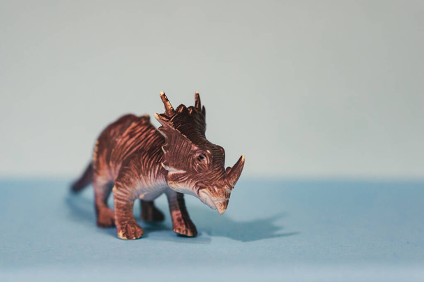 A closeup shot of a brown toy Triceratops isolated on a grey background - Φωτογραφία, εικόνα