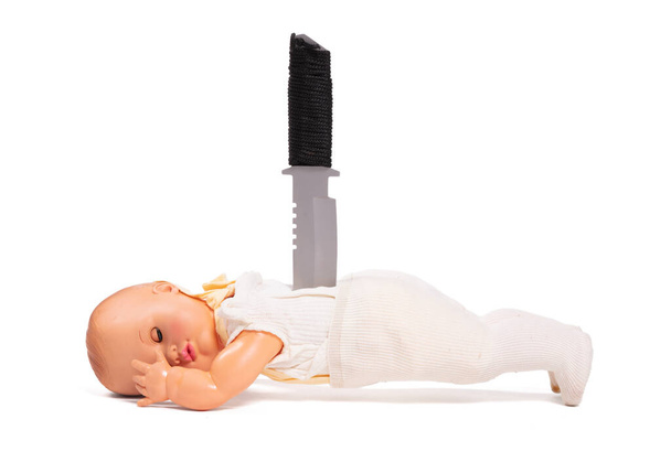 Разбитая старая кукла, нож сзади, изолированный на белом фоне - Фото, изображение