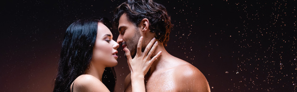 oldal kilátás szexi nő közelében fiatal félmeztelen férfi eső alatt sötét háttér, banner - Fotó, kép