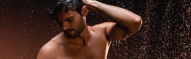 сексуальный мужчина без рубашки позирует с закрытыми глазами под дождем на темном фоне, баннер - Фото, изображение