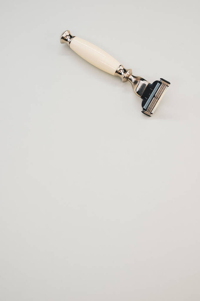 A vertical shot of a beige and black razor isolated on a softer tan background - Fotografie, Obrázek
