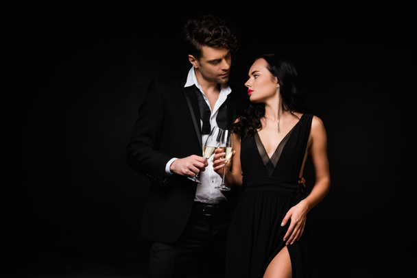 sexy pareja sosteniendo copas de champán aislado en negro  - Foto, Imagen