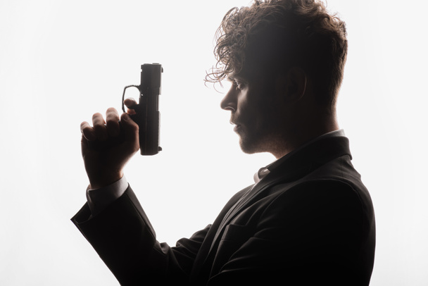 vista laterale di uomo riccio in formale usura pistola tenuta isolato su bianco - Foto, immagini