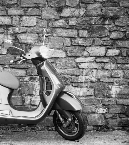Beautiful classic design gray color Vespa scooter with beige seat cushion parking on near  stone wall background. SALZBURG, AUSTRIA - Foto, Imagen