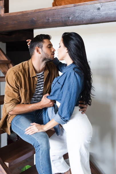 young stylish couple kissing on wooden stairs at home with closed eyes - Fotografie, Obrázek