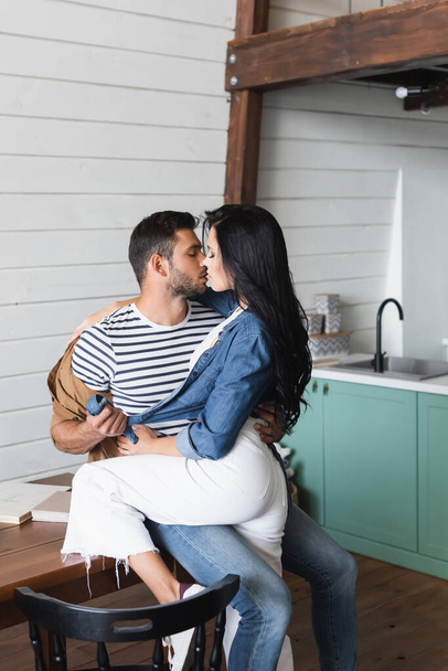 young couple in stylish casual clothes hugging and kissing in kitchen - Foto, Imagen
